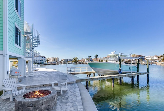 view of dock with a water view, a patio area, and a fire pit