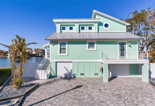 back of property featuring a garage, a balcony, and a water view