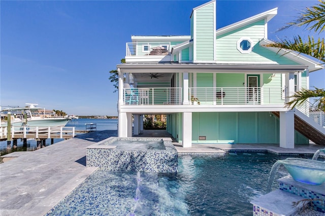 back of property featuring pool water feature, ceiling fan, a hot tub, a water view, and a patio area