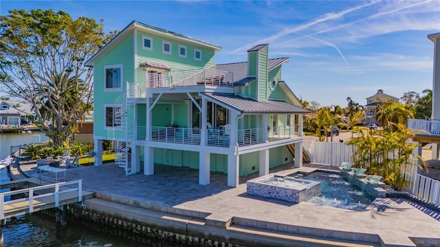 rear view of house featuring a balcony, a water view, a patio area, and an outdoor fire pit