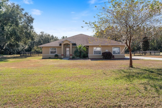 view of front of house with a front yard, stucco siding, fence, and a shingled roof