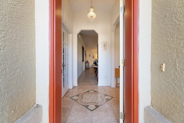 hall featuring light tile patterned floors and lofted ceiling