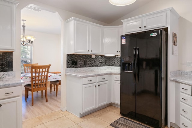 kitchen with light stone countertops, tasteful backsplash, black refrigerator with ice dispenser, an inviting chandelier, and white cabinetry