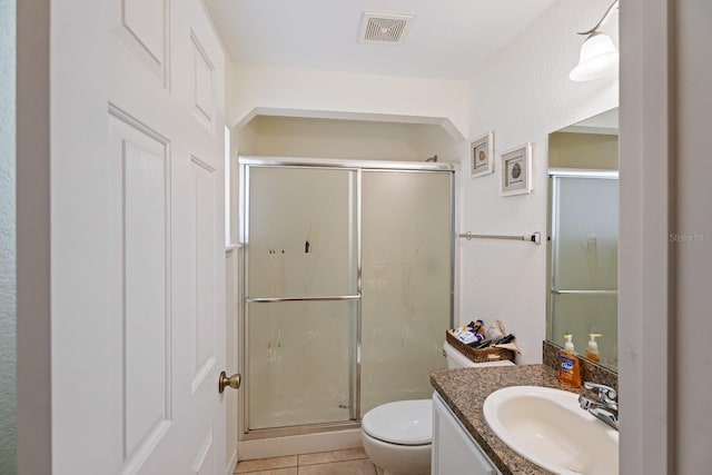 bathroom featuring tile patterned floors, a shower with door, vanity, and toilet