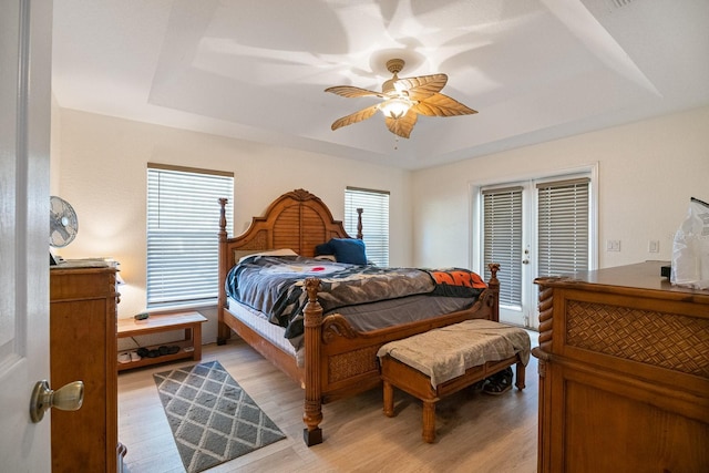 bedroom featuring french doors, light hardwood / wood-style flooring, multiple windows, and ceiling fan