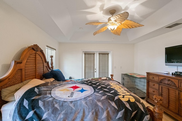 bedroom with ceiling fan, french doors, and a tray ceiling