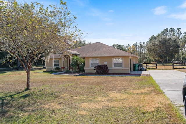 view of front of property with a front lawn, driveway, stucco siding, and fence