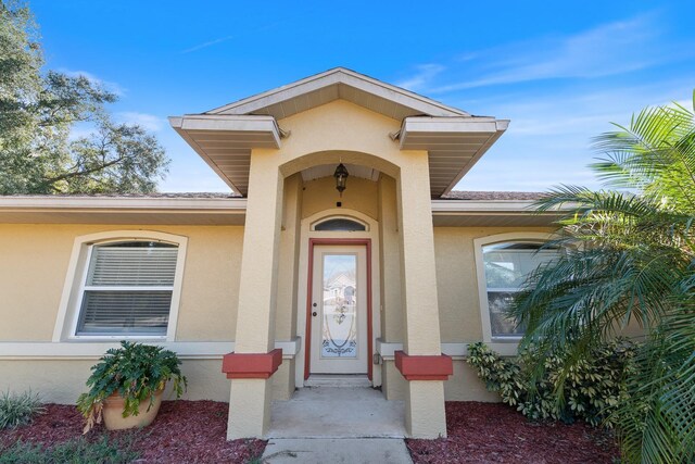 property entrance featuring a shingled roof and stucco siding