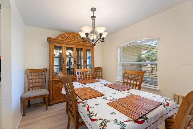 dining area with light wood-style floors and an inviting chandelier