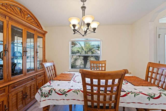 dining space featuring a notable chandelier, arched walkways, and lofted ceiling