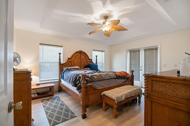 bedroom featuring light wood finished floors and a raised ceiling
