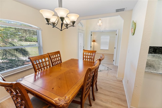 dining area with light wood finished floors, baseboards, visible vents, and an inviting chandelier