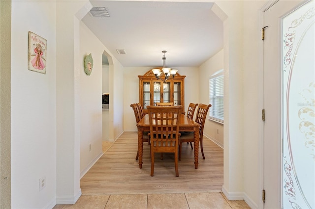 dining room featuring light tile patterned floors, arched walkways, a notable chandelier, and visible vents