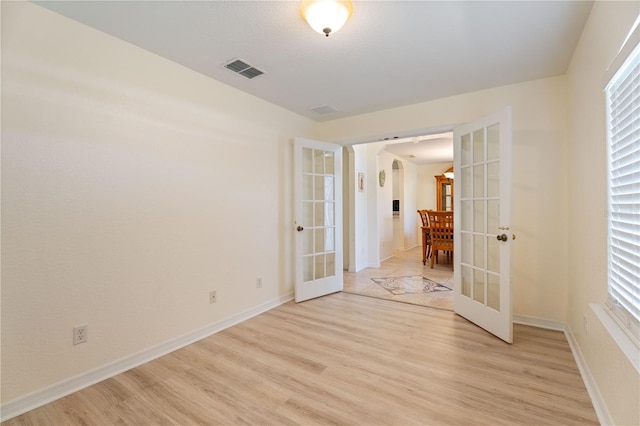 unfurnished room featuring french doors, light wood-style flooring, baseboards, and visible vents