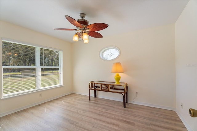 unfurnished room featuring baseboards, light wood-style floors, and a ceiling fan