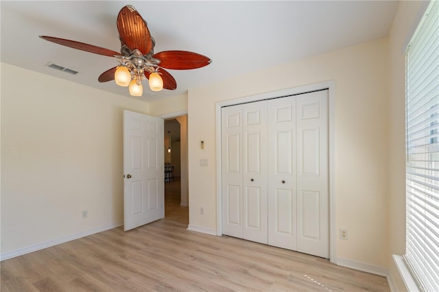 unfurnished bedroom featuring baseboards, light wood finished floors, visible vents, a ceiling fan, and a closet
