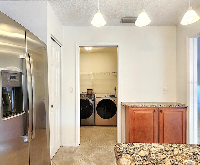 laundry room with light tile patterned flooring, washing machine and dryer, and a textured ceiling