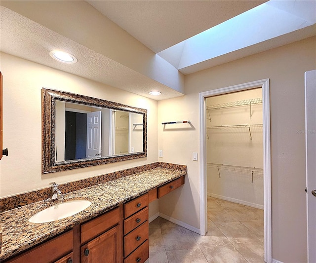 bathroom with tile patterned flooring, vanity, and a textured ceiling