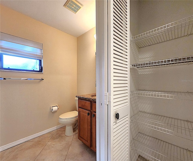 bathroom with toilet, vanity, and tile patterned floors