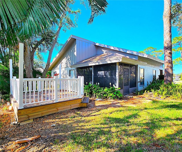 back of property featuring a sunroom, a yard, and a wooden deck