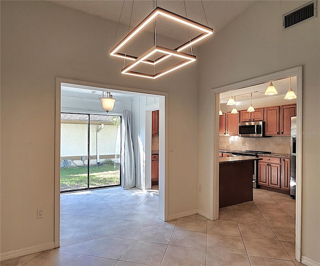 kitchen featuring decorative backsplash, light tile patterned floors, stainless steel appliances, and pendant lighting