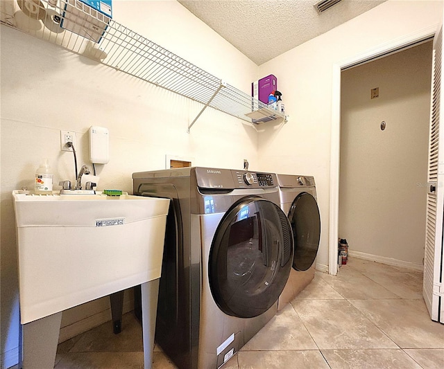 laundry area featuring light tile patterned floors, a textured ceiling, and separate washer and dryer