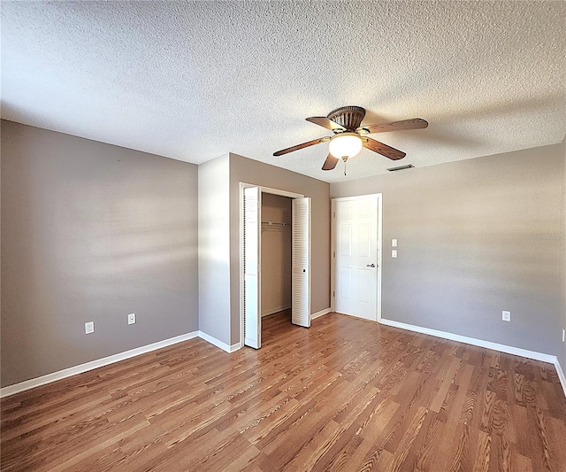 unfurnished bedroom with hardwood / wood-style floors, ceiling fan, and a textured ceiling