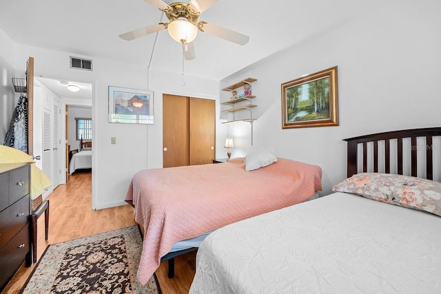 bedroom with a closet, light hardwood / wood-style floors, and ceiling fan