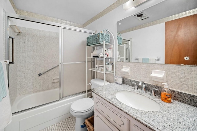 full bathroom with vanity, shower / bath combination with glass door, backsplash, tile patterned floors, and toilet