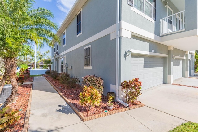 view of property exterior with a balcony, central AC unit, and a garage