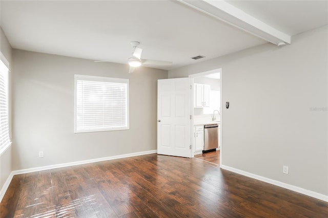 spare room with beamed ceiling, ceiling fan, plenty of natural light, and dark wood-type flooring