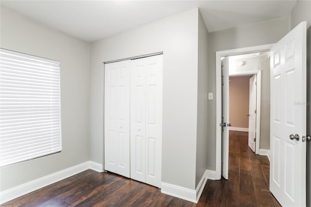 unfurnished bedroom featuring a closet and dark wood-type flooring