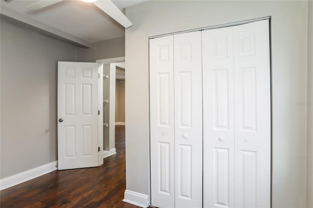 unfurnished bedroom featuring ceiling fan, a closet, and dark wood-type flooring