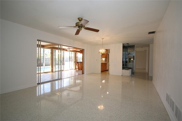 spare room featuring ceiling fan with notable chandelier