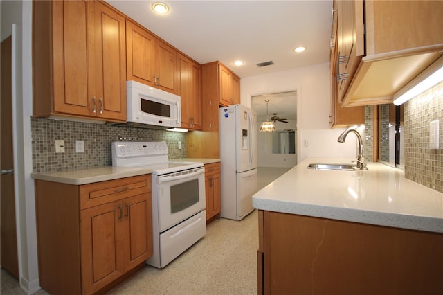 kitchen with light stone counters, white appliances, sink, and backsplash