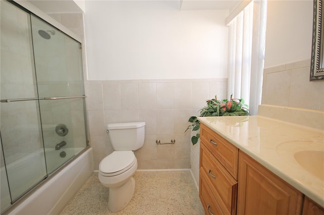 full bathroom with vanity, tile walls, bath / shower combo with glass door, and toilet