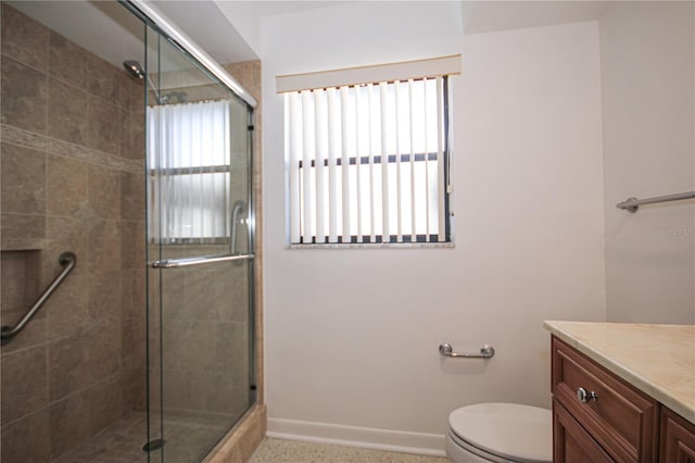 bathroom featuring vanity, a shower with door, and toilet