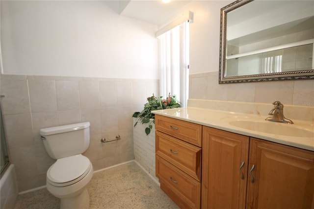 full bathroom featuring vanity, tile walls, toilet, and combined bath / shower with glass door