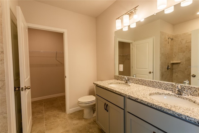 bathroom with tile patterned flooring, vanity, toilet, and tiled shower