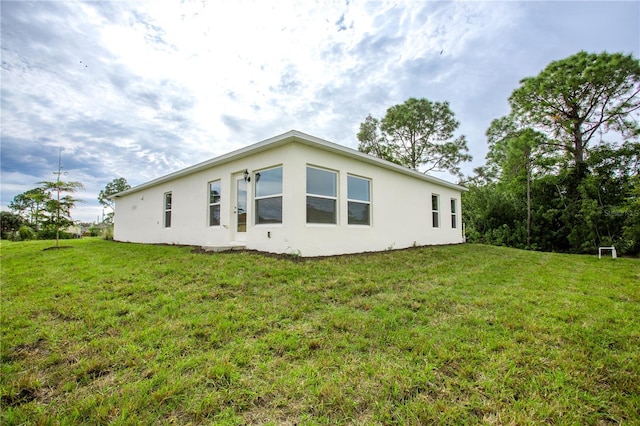 447 Raymer St, Lehigh Acres, FL 33974 - view of side of home with stucco siding and a yard