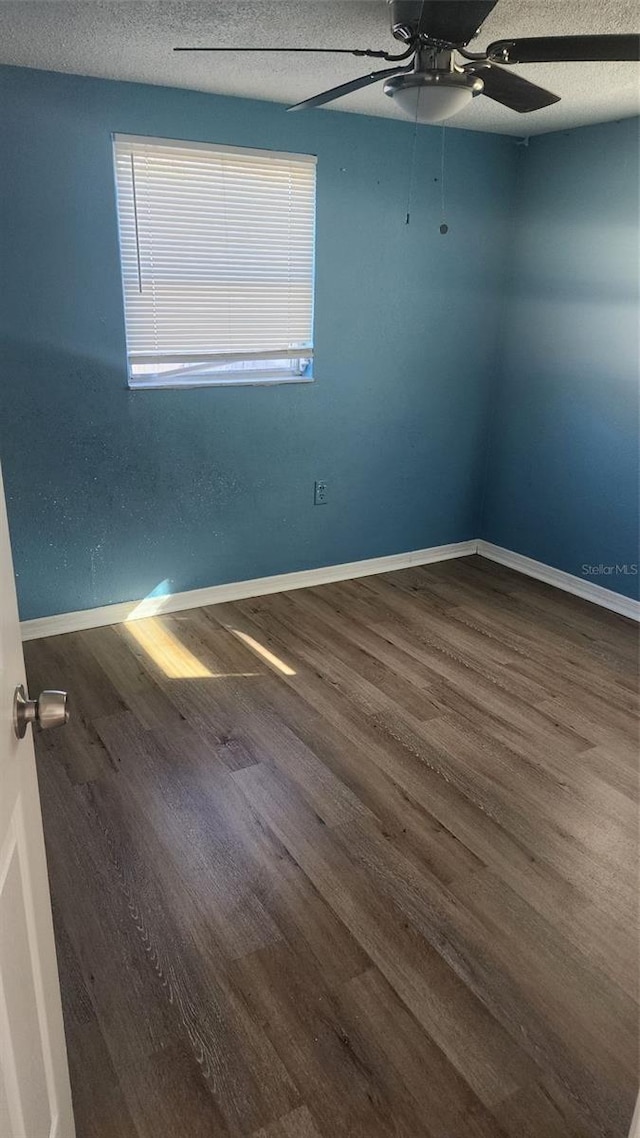 unfurnished room with a textured ceiling, ceiling fan, and dark wood-type flooring