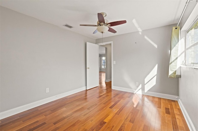 empty room featuring plenty of natural light, ceiling fan, and light wood-type flooring