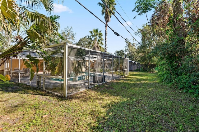 view of yard with a fenced in pool and glass enclosure