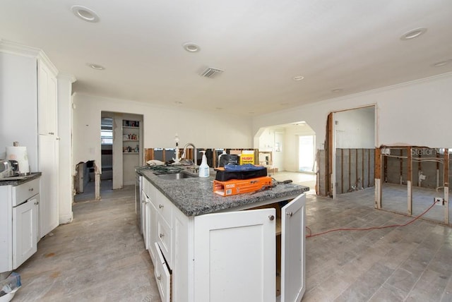 kitchen with plenty of natural light, white cabinetry, sink, and a center island with sink