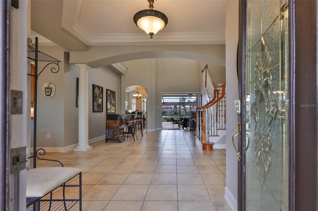 entryway with ornate columns, ornamental molding, light tile patterned floors, and a chandelier