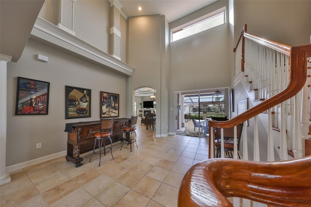 foyer entrance with light tile patterned floors and a towering ceiling