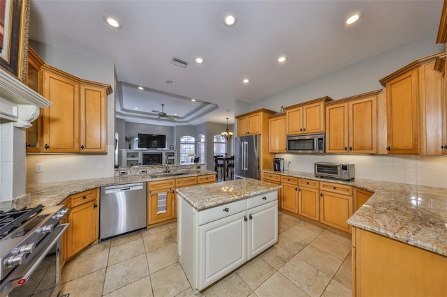 kitchen featuring stainless steel appliances, a tray ceiling, light stone countertops, and white cabinets