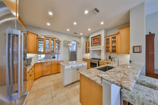 kitchen with a kitchen island, sink, kitchen peninsula, stainless steel appliances, and light stone countertops