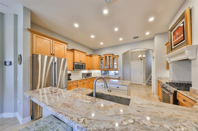 kitchen with light stone counters, appliances with stainless steel finishes, sink, and decorative backsplash