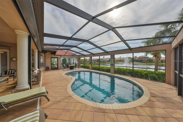 view of pool with a patio, glass enclosure, and a water view